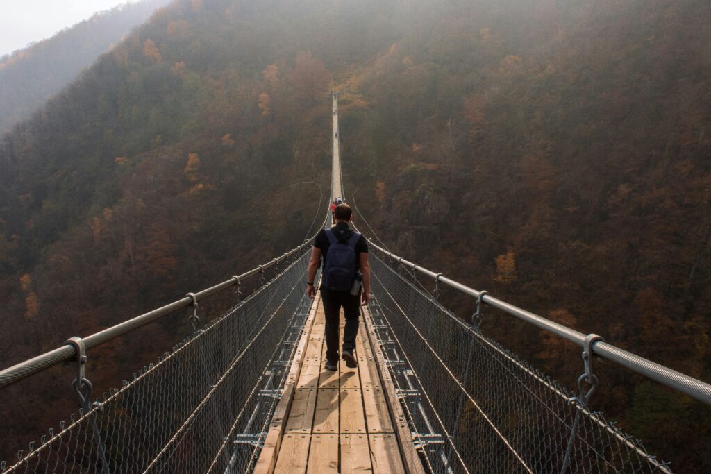 man walking on high suspension bridge