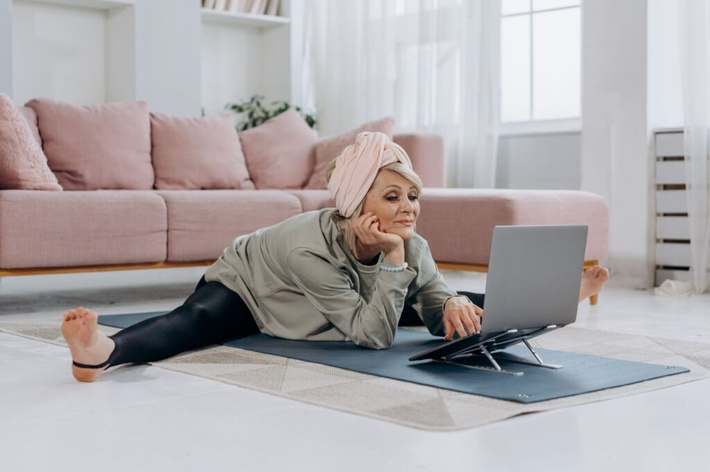 woman sitting in a split on the floor in front of a laptop