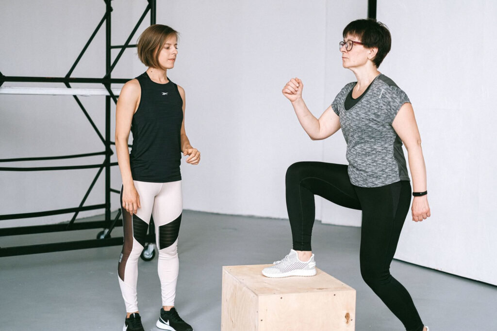 woman stepping up on a box exercising with personal trainer