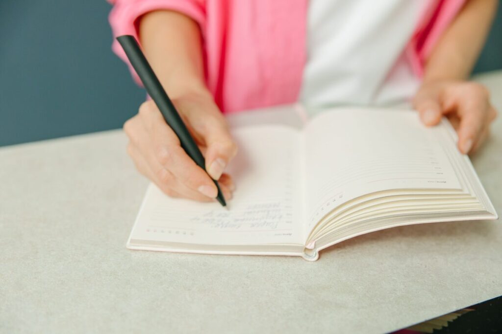 woman writing-journal-pen-pink-sleeve-optimized