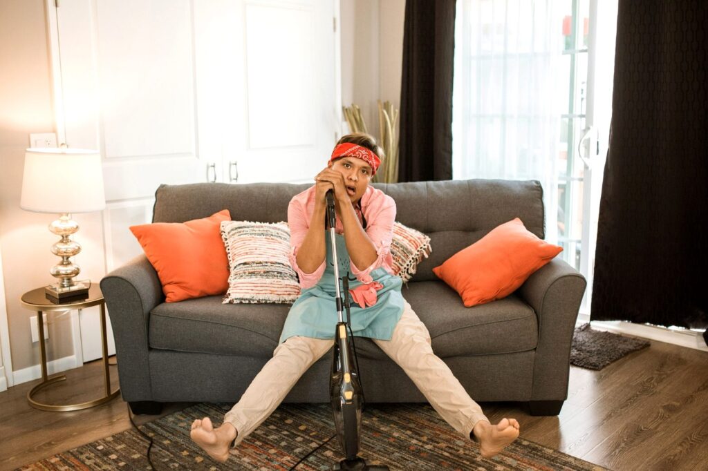 woman sitting exhausted on couch leaning over a vacuum cleaner