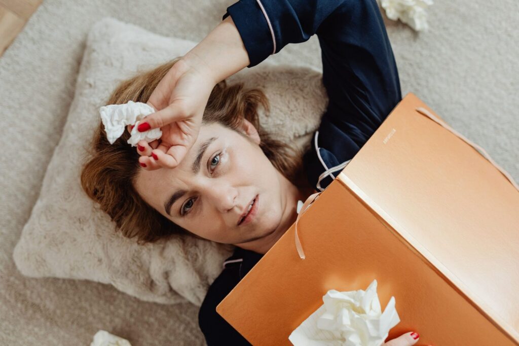 stressed out woman laying down with notebook over her chest