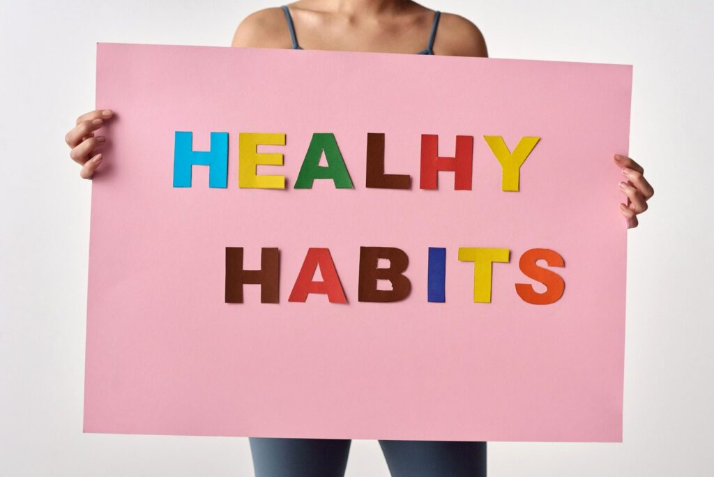 woman holding big pink sign that says healthy habits