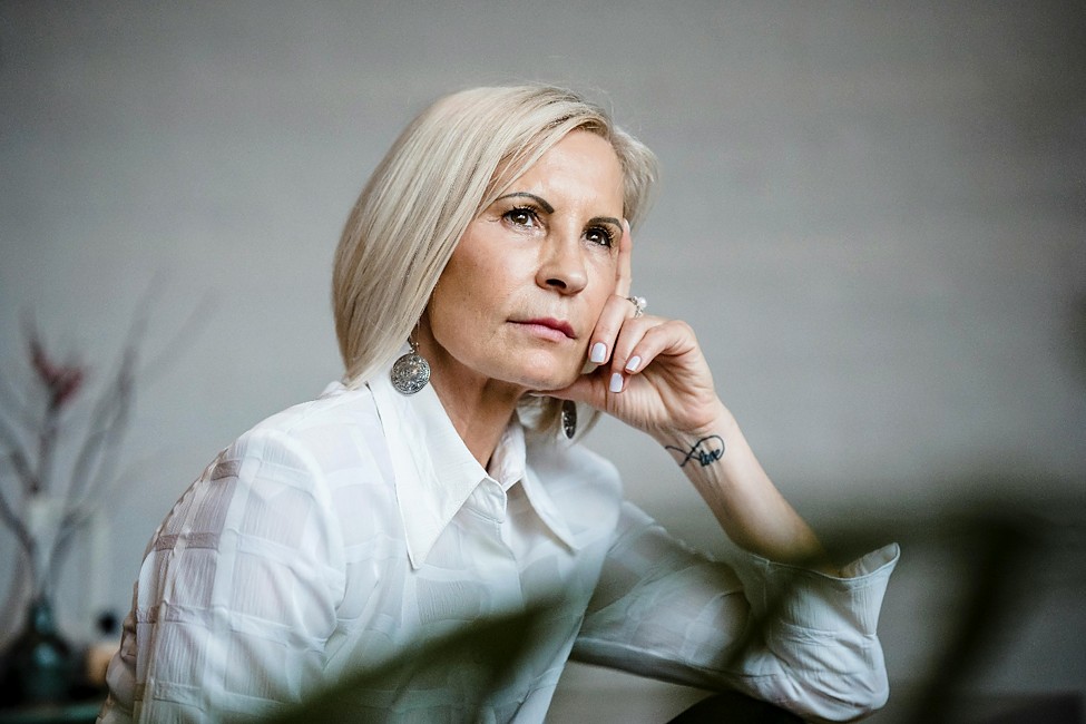 woman over 50 in white shirt sitting and pondering