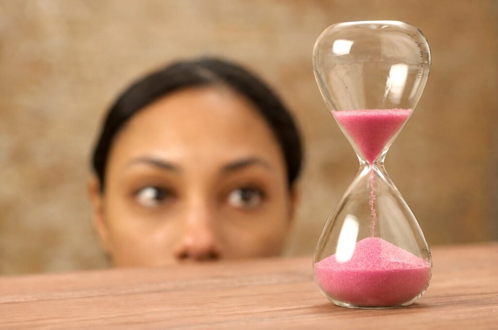 woman staring at pink hourglass